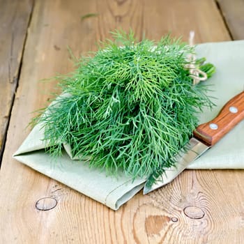 Fresh green dill on a napkin with a knife on the background of wooden boards