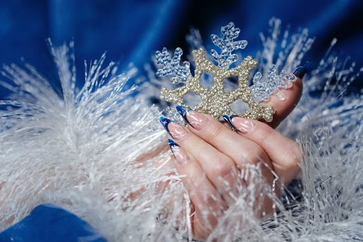 Female hand with beautiful manicure holding a snowflake shot closeup