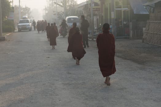 INLE LAKE, MYANMAR - 08 JAN 2014: Young monks gather food on early morning almsround. Offering food is one of the oldest and most common rituals in Buddhism.