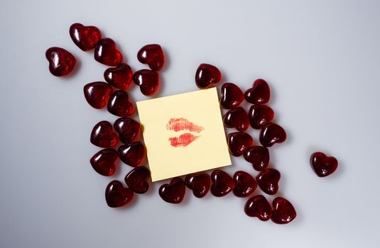 Imprint of female lips with red lipstick on a sticker surrounded by hearts from glass