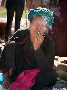 INLE LAKE, MYANMAR (BURMA) - 07 JAN 2014: Local Burmese Intha woman smoke cheroot cigar. Cheroots are Burmese facial feature.