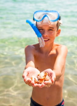 Boy wearing snorkeling gear showing seashells