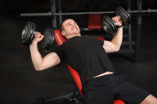 Handsome young man doing Dumbbell Incline Bench Press workout in gym