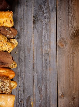 Border of Various Buns, Baguette, Poppy Seed and Sesame Buns, Rye and Whole Wheat Bread closeup on Rustic Wood background