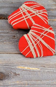 Two Handmade Red Valentine  Hearts Decorated with Threads isolated on Rustic Wood background