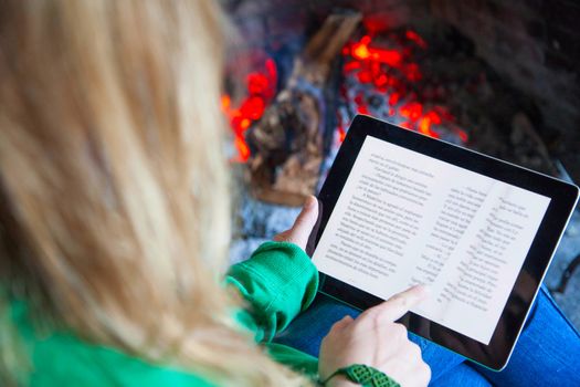 Woman with a tablet fire place and reading