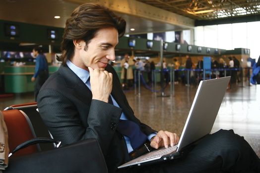 Businessman working on laptop computer at airport
