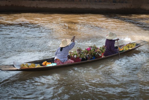 Floating vendors on small  long wooden boat  with fresh vegetables and flowers row at dark water