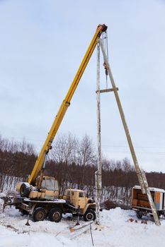 Construction of power lines using a mobile crane in a winter snowy forest 