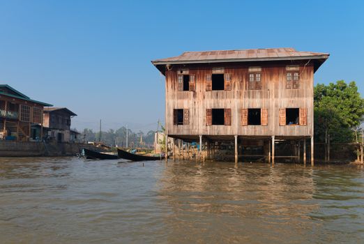 Traditional stilts wooden house and boat of Intha people in water on Inle lake, Myanmar (Burma) 