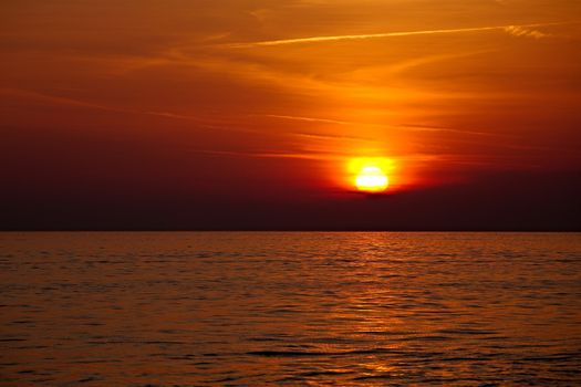 Setting sun in cloudy sky at the sea