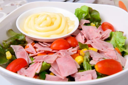 the fresh salad with ham in white bowl