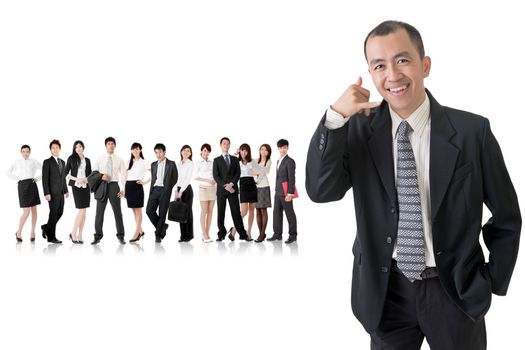 Mature businessman give you a gesture of call and standing in front of his team on studio white background.