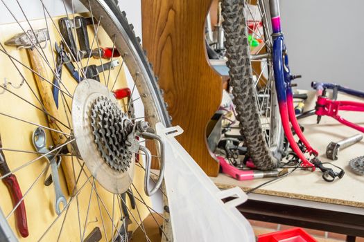 Wheels and bicycle parts over workshop table in the restoration process of a damaged bike