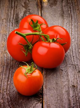 Small Ripe Red Tomatoes with Stems isolated on Rustic Wooden background