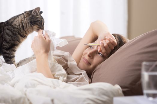 Sick woman with medical thermometer lying on bed