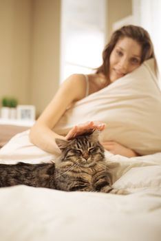 Woman relaxing on bed with her cat on the summer warm day. 