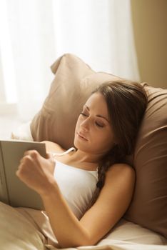 Woman lying in bed while reading a book 