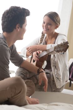 Beautiful girl playing guitar for her boyfriend at home 