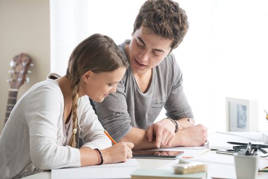 Teen boy and girl sitting together and studying 