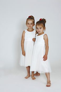 Happy sisters in the studion in white dresses.