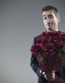 Man holding out large bouquet of red roses 