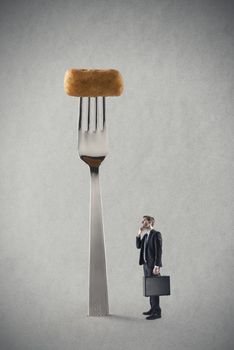 Young businessman thinking in front a big fork with fried potato croquet