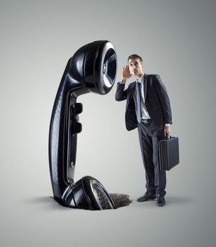 Young businessman and huge retro phone receiver.