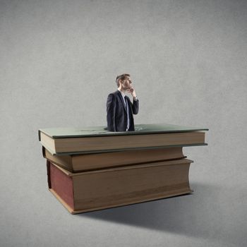 Businessman breaking through a pile of books.