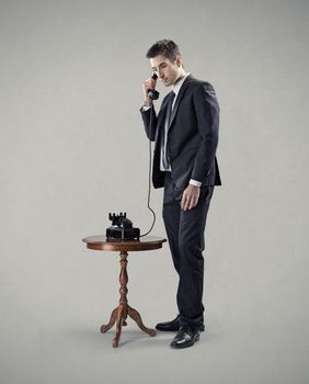 Elegant businessman on the phone on gray background.