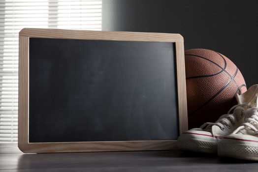 White sneakers with basketball and blank blackboard with copyspace.