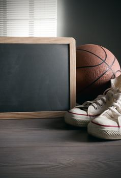 White sneakers with basketball and blank blackboard with copyspace.