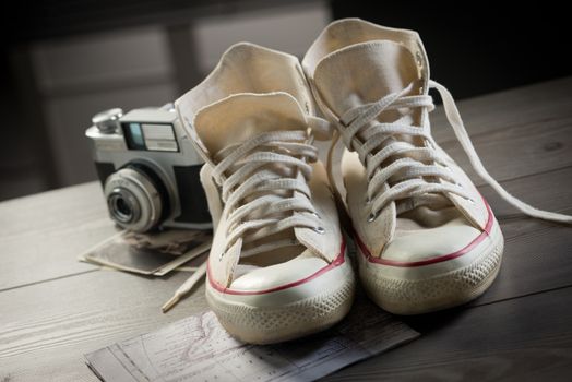 Canvas shoes with vintage camera and world map, youth adventure trip concept.