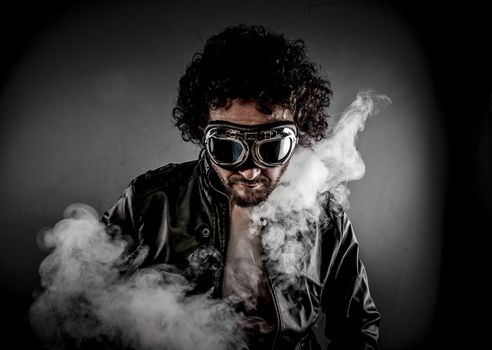 Sensual male biker with sunglasses era dressed Leather jacket, huge smoke over dark background