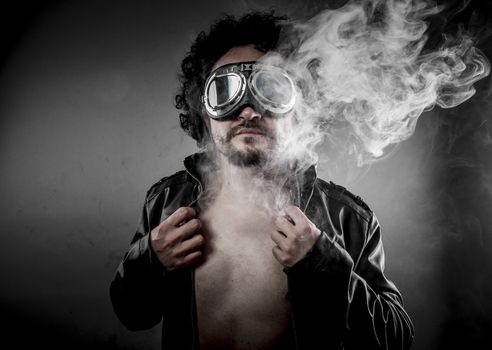 Sensual male biker with sunglasses era dressed Leather jacket, huge smoke over dark background