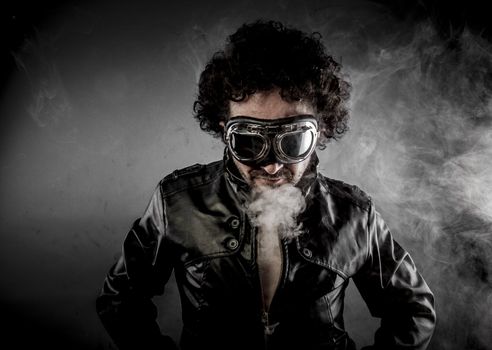 Male biker with sunglasses era dressed Leather jacket, huge smoke over dark background