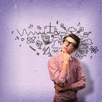 young man scientist in glasses thinking. next to it various painted symbols