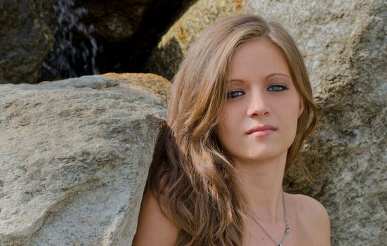 Headshot of pretty blue eyed, brunette girl against rocks