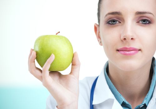 Portrait of a professional female doctor holding fresh green apple