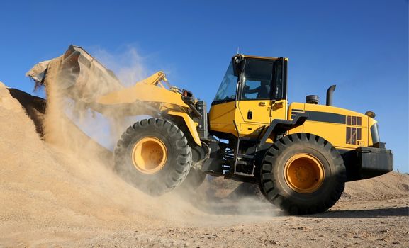 Front end loader dumping stone and sand in a mining quarry