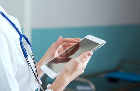 Close up of a female doctor in scrubs using digital tablet.