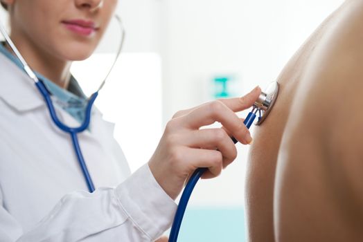 Female doctor listening man's back through stethoscope 