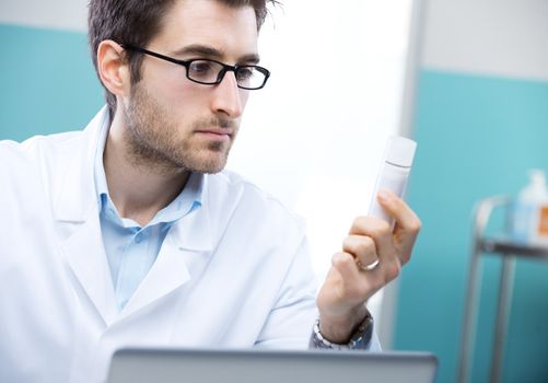 Young doctor thinking and examining prescription medicines.