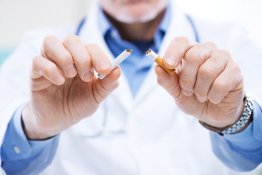 Senior doctor breaking a cigarette, stop smoking concept.