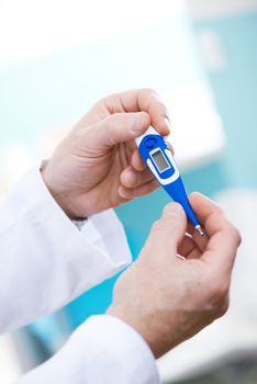 Doctor checking temperature with a thermometer, hands close-up.