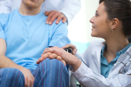 Young female doctor comforting a young patient on wheelchair.