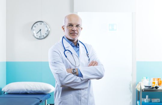 Senior confident doctor in a clinic with arms crossed.