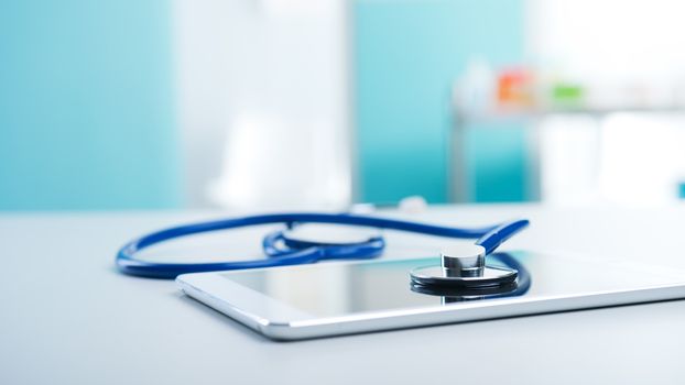 Medical equipment: blue stethoscope and a digital tablet.