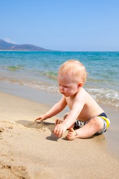 Happy baby boy playing on a beach