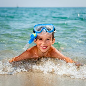 Happy boy wearing snorkeling gear lying in the sea